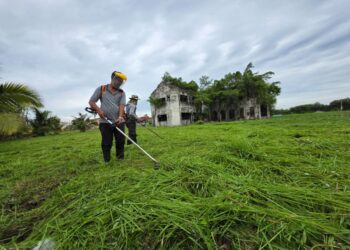 PEKERJA Jabatan Kerja Raya (JKR) Teluk Intan menjalankan kerja-kerja memotong rumput di sekitar Istana Lama Raja Muda di  Teluk Intan, Perak.–  UTUSAN/AIN SAFRE BIDIN