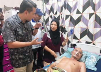 ZULIANA MOHAMAD memberikan minuman susu khas kepada suaminya Abdul Khizad Abdul Yazid ketika kunjungan Syed Hussein Syed Abdullah (kiri) di kediamannya di Taman Orked, Kluang, Johor, semalam.