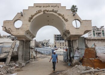 SEORANG lelaki berjalan di bawah pintu gerbang bangunan Majlis Perundangan Pihak Berkuasa Palestin yang kini menempatkan kem pelarian sementara di Gaza City.-AFP