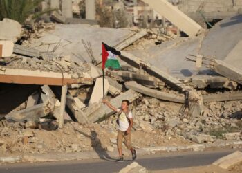 SEORANG kanak-kanak lelaki mengibarkan bendera kebangsaan Palestin ketika berjalan melalui runtuhan bangunan yang musnah di kem pelarian Bureij, tengah Semenanjung Gaza. - AFP