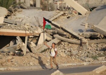 SEORANG kanak-kanak lelaki mengibarkan bendera kebangsaan Palestin ketika berjalan melalui runtuhan bangunan yang musnah di kem pelarian Bureij, tengah Semenanjung Gaza. - AFP