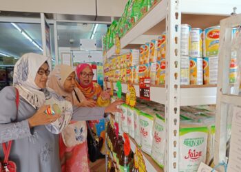 AIRIN Yusmira Mohd. Yusof (kanan) melayan pelanggan terdiri daripada warga emas melihat sebahagian barangan yang boleh ditebus melalui bantuan SARA ketika ditemui di Pasar Mini Sri Layang, Rembau baru-baru ini.-UTUSAN/NOR AINNA HAMZAH.