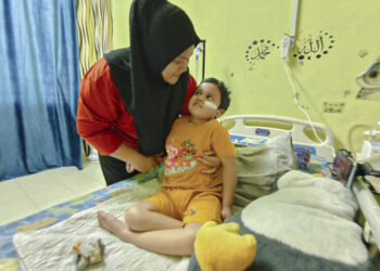 ENGKU Noor Wahidah Engku Anuar memeriksa keadaan Putri Nur Elyna Soffiya yang menderita akibat nanah dalam otak di rumah mereka di Kampung Dusun Melintang, Manir, Terengganu. – UTUSAN/NURSYASYA NADHIRAH ZABIDI