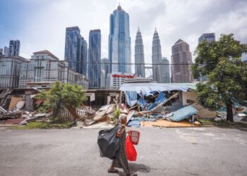 Seorang wanita melewati deretan rumah yang sebahagiannya telah dirobohkan di Kampung Sungai Baru, Kuala Lumpur, semalam. 
– UTUSAN/MUHAMAD IQBAL ROSLI