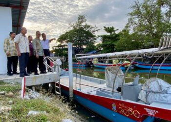 MOHAMAD Abdul Hamid (dua dari kanan) meninjau keadaan bot yang akan diagihkan kepada nelayan pada majlis penyerahan manfaat SIMP di Kampung Binjai, Sungai Bayan Lepas, Pulau Pinang.