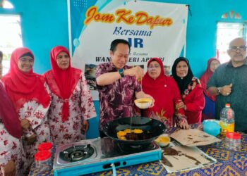 AHMAD Maslan membuat kuih goyang pada program Jom ke Dapur di Pusat Daerah Mengundi (PDM) Api-Api, di Pontian, Johor, hari ini.