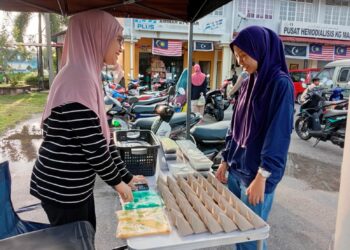 FATIN Nabilah Ibrahim (kiri) melayani pelanggan di gerai nasi lemaknya di Pasar Maras, Kuala Nerus, Terengganu. – UTUSAN/ERMA YUSNIDA JUSOH.