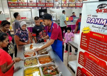 KAKITANGAN kafeteria HTJS, Muhammad Ikram Mohd Harun melayani pelanggan yang mendapatkan Menu Rahmah yang ditawarkan di kafeteria tersebut hari ini. - UTUSAN/MOHD. SHAHJEHAN MAAMIN