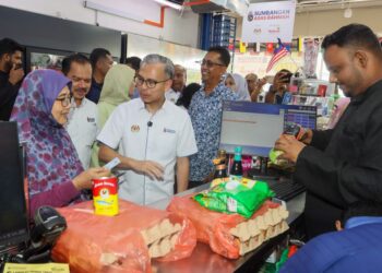 FAHMI Fadzil (tiga dari kiri) berbual bersama seorang warga emas yang baru sahaja membuat penebusan bantuan SARA di sebuah pasar raya mini di Kubang Semang, Bukit Mertajam, Pulau Pinang.-UTUSAN/DANIAL SAAD
