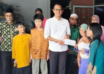 MOHD. FARED Mohd. Khalid (berdiri, tengah) menyampaikan sumbangan kepada Marlina M. Sai ketika mengunjungi kediaman mereka di Taman Sri Skudai, Johor Bahru.