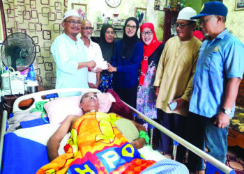 MOHD. Youzaimi (kiri) menyerahkan sumbangan kepada Zalia (empat dari kanan) ketika melawat Kamaruzaman yang terlantar akibat kanser otak di Kampung Tenglu, Mersing, Johor.