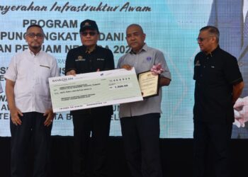 Mohd. Dusuki Mokhtar (dua dari kiri) menyerahkan replika cek sumbangan kepada Pengerusi KRT Taman Desa Kemumin, Razali Abdul Rahman pada Majlis Penyerahan Infrastruktur Awam Program Kampung Angkat Madani Jabatan Peguam Negara 2025 di Kampung Padang Tembak, Kelantan. - UTUSAN /ROSMIZAN RESDI