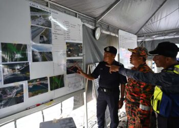 MOHD. Razi Rosli (kiri) bersama Mohd. Khairi Mat Resad (tengah) meneliti carta lokasi kebocoran gas butana di Pos Kawalan Tempat Kejadian (PKTK), Kerteh, Kemaman, Terengganu. - UTUSAN / NIK NUR IZZATUL HAZWANI NIK ADNAN