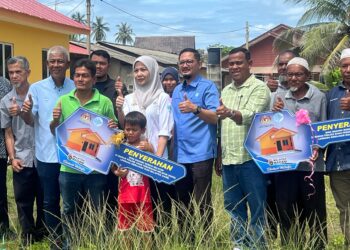 HAMDAN Mamat (tengah) bersama warga nelayan meraikan dua penerima kunci rumah bina baharu di Kampung Pantai Perupuk, Bachok, Kelantan. - UTUSAN/TOREK SULONG