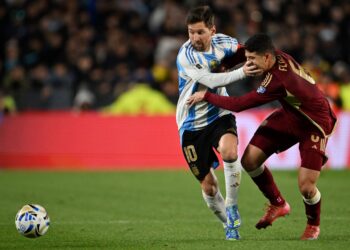 Penyerang Argentina, Lionel Messi (kiri( dan pemain tengah Venezuela Leonardo Flores berebut bola semasa perlawanan bola sepak kelayakan Piala Dunia FIFA 2026 Amerika Selatan antara Argentina dan Venezuela di stadium Mas Monumental di Buenos Aires, hari ini. - AFP