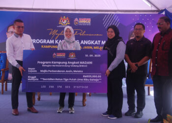 KHAIDHIRAH Abu Zahar menerima replika cek daripada Nur Azlin Mohamad Awal (kanan) pada Peluncuran Program Kampung Angkat Madani (KAM 2.0) di Kampung Bukit Katong, Jasin, Melaka. - UTUSAN/AMRAN MULUP