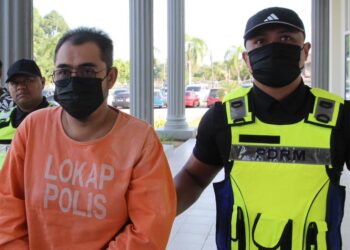 TERTUDUH (kiri) semasa dibawa polis untuk prosiding perbicaraan di Mahkamah Sesyen Pasir Mas, Kelantan. - UTUSAN/KAMARUL BISMI KAMARUZAMAN