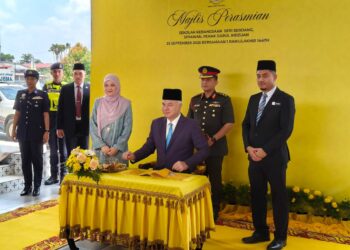 SULTAN Nazrin Muizzuddin Shah menandatangani buku lawatan sempena perasmian SK Seri Serdang di Sitiawan, hari ini. - UTUSAN