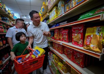 NGA Kor Ming bersama anak yatim membeli barang keperluan di sebuah pasar mini di Ipoh hari ini. - UTUSAN