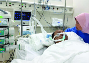 MOHD. Basri Ibrahim dijaga kakaknya, Nurainun ketika dirawat di Unit Rawatan Rapi Hospital FV Ho Chi Minh, Vietnam, Jumaat lalu.
– IHSAN KELUARGA