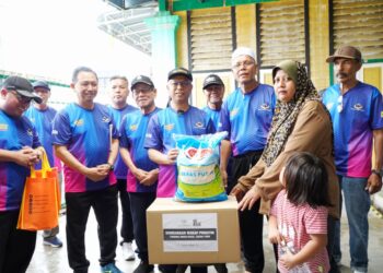 RIDZWAN Bakar (tengah)  dan Meor Redwan Mahayudin (tiga dari kiri) menyampaikan bantuan keperluan asas pada Program Santuni Komuniti Madani di Teluk Intan hari ini. - UTUSAN