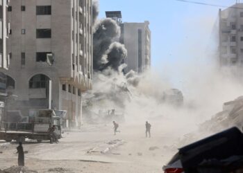 PENDUDUK Palestin melarikan diri ketika tentera Israel membedil sebuah bangunan di Gaza City. - AFP