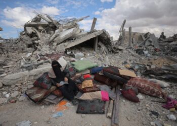 SEORANG wanita Palestin duduk di hadapan bangunan runtuh di Khan Younis, selatan Gaza. – AFP