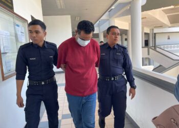 TERTUDUH diiringi anggota polis ketika dihadapkan ke Mahkamah Majistret Ayer Keroh, Melaka atas pertuduhan menggunakan dadah. - UTUSAN/ MUHAMMAD SHAHIZAM TAZALI