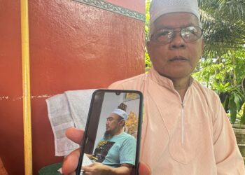 MAHMUD Talib menunjukkan gambar arwah anaknya, Muhammad Husni ketika ditemui di rumahnya di Taman Bendahara, Kampung Sungai Kajang, Batu Pahat, Johor semalam.