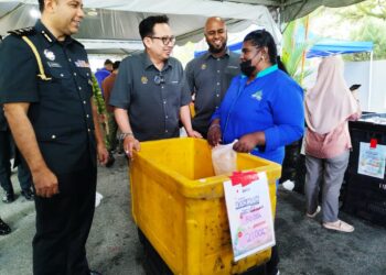 KAMALLUDIN Ismail (dua dari kiri) menyantuni pengunjung yang membeli barangan di pasar jualan Rahmah di Bangunan Persekutuan Ipoh, Perak hari ini.-UTUSAN/FADZIL ZAINOL