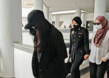 TERTUDUH diiringi Pegawai SPRM dibawa keluar dari Mahkamah Sesyen Ayer Keroh, Melaka atas pertuduhan secara berasingan menerima suapan sebagai upah memproses permohonan pembiayaan peribadi pelanggan melebihi had kelayakan ditetapkan institusi kewangan. - UTUSAN/AMRAN ALI.