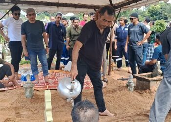 AHLI keluarga menyiram air mawar ke atas pusara Aziz Awang dan Hasnah Mat Nong yang dikebumikan dalam satu liang lahad di Tanah Perkuburan Islam Kuala Kemaman, Terengganu. – MINGGUAN/NIK NUR IZZATUL HAZWANI NIK ADNAN