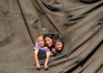 PIX 1 - KANAK-kanak mengintai melalui lubang kanvas khemah di sebuah kem pelarian di utara Nuseirat, tengah Gaza.- AFP