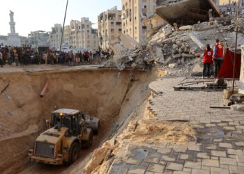 ANGGOTA Jawatankuasa Palang Merah Antarabangsa memerhati ketika penduduk Palestin menggunakan jentolak untuk mencari mayat di Khan Younis, selatan Semenanjung Gaza.-AFP