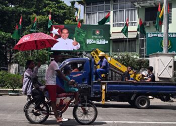 PENDUDUK memandu melepasi papan iklan kempen pilihan raya memaparkan Pengerusi Parti USDP, Khin Yi menjelang permulaan kempen pilihan raya di Yangon.-AFP