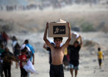 SEORANG budak lelaki Palestin membawa kotak bantuan yang diterima daripada pusat agihan Yayasan Kemanusiaan Gaza (GHF) berhampiran koridor Netzarim.- AFP