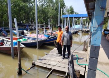 ABDUL Aziz Mohd Nor (kiri) menunjukkan bot-bot milik nelayan ketika ditemui di Jeti Nelayan Tampok Laut, di Benut, Pontian, Johor, semalam.