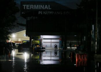 SEORANG pekerja di Terminal Penumpang Pulau Ketam, Klang, Selangor duduk sambil menunggu air laut surut akibat berlakunya fenomena air laut pasang besar pagi tadi. -UTUSAN/AFIQ RAZALI