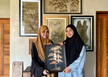 NOR Padilah Afandi (kiri) dan Rafidah Nani menunjukkan salah satu hiasan dinding yang dihasilkan menggunakan duit syiling ketika ditemui di Kampung Temeris, Kuala Pilah. – UTUSAN/NOR SHAFIQAH MOHD. GHAZALI