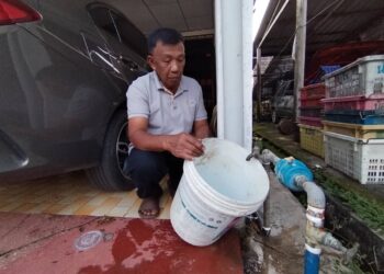 SAMSUDIN Mohamad menadah bekalan air di rumahnya di Perumahan Awam Pelagat 3, Besut, Terengganu. – UTUSAN/WAN ZURATIKAH IFFAH WAN ZULKIFLI