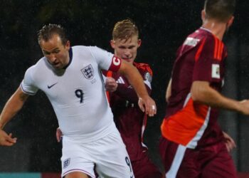 Kapten England, Harry Kane (kiri) cuba melepasi halanga pemain Latvia, Maksims Tonisevs dalam aksi kelayakan Piala Dunia 2026 di Riga, Latvia, semalam. - AFP