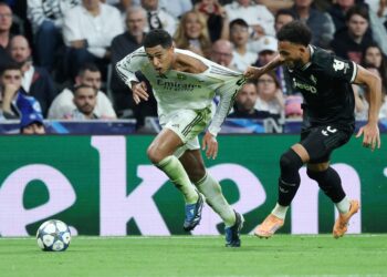 Pemain Real Madrid, Jude Bellingham ditarik bajunya oleh pertahanan Juventus, Lloyd Kelly bagi menghalang pergerakkan pemain itu pada aksi Liga Juara-Juara di Santiago Bernabeu.-AFP