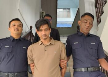 TERTUDUH dibawa keluar dari Mahkamah Majistret Ayer Keroh selepas dijatuhi hukuman denda RM3,500 kerana mencederakan kekasihnya warga Thailand menggunakan kerusi dan tali pinggang. - UTUSAN/AMRAN ALI