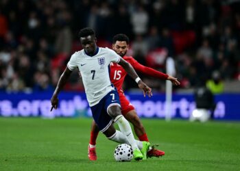 Pemain tengah England, Bukayo Saka bertarung untuk mendapatkan bola dengan pemain pertahanan Wales, Jay Dasilva semasa perlawanan bola sepak persahabatan antara England dan Wales di Stadium Wembley, hari ini. - AFP