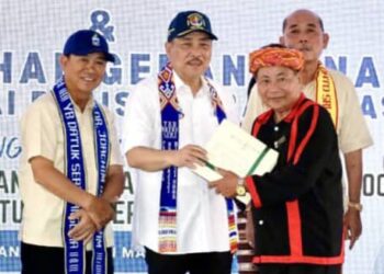 HAJIJI Noor menyerahkan 468 geran tanah di bawah Program Pengukuran Tanah Anak Negeri Sabah (PANTAS) kepada penduduk Pitas. - UTUSAN/HARDY JOE