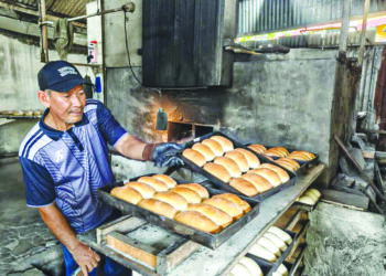 Ramli Embong mengeluarkan roti bakar dapur kayu di kedainya di Kampung Bukit Tinggal, Kuala Nerus. - MINGGUAN/ERMA YUSNIDA JUSOH