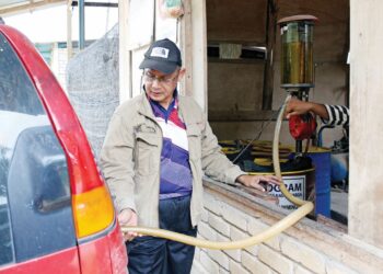 PEKERJA pam membantu seorang penduduk membeli petrol bersubsidi di Dabong, Kuala Krai, Kelantan. –  UTUSAN/KAMARUL BISMI KAMARUZAMAN