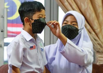 NOR Delisha Adelea membantu adiknya, Mohamad Dhani Aidan memakai pelitup muka di rumah mereka di Jelutong, Georgetown sebelum ke sekolah sebagai langkah membendung peningkatan kes influenza dalam kalangan murid sekolah di seluruh negara. 
– UTUSAN/Danial Saad