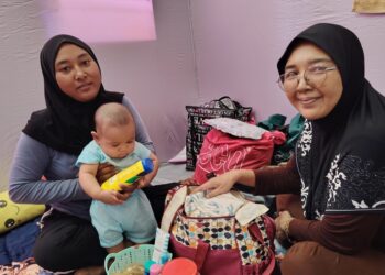 NORATIKA Hairolnizam (kiri) memangku Arif Hakimi bersama ibunya, Noratikah Abd. Aziz di PPS SK Melayu Raya, Pekan Nanas, Pontian, Johor, hari ini.
