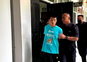 Suspek (kiri) dibawa keluar dari kamar mahkamah selepas tahanan remannya dibenarkan.
